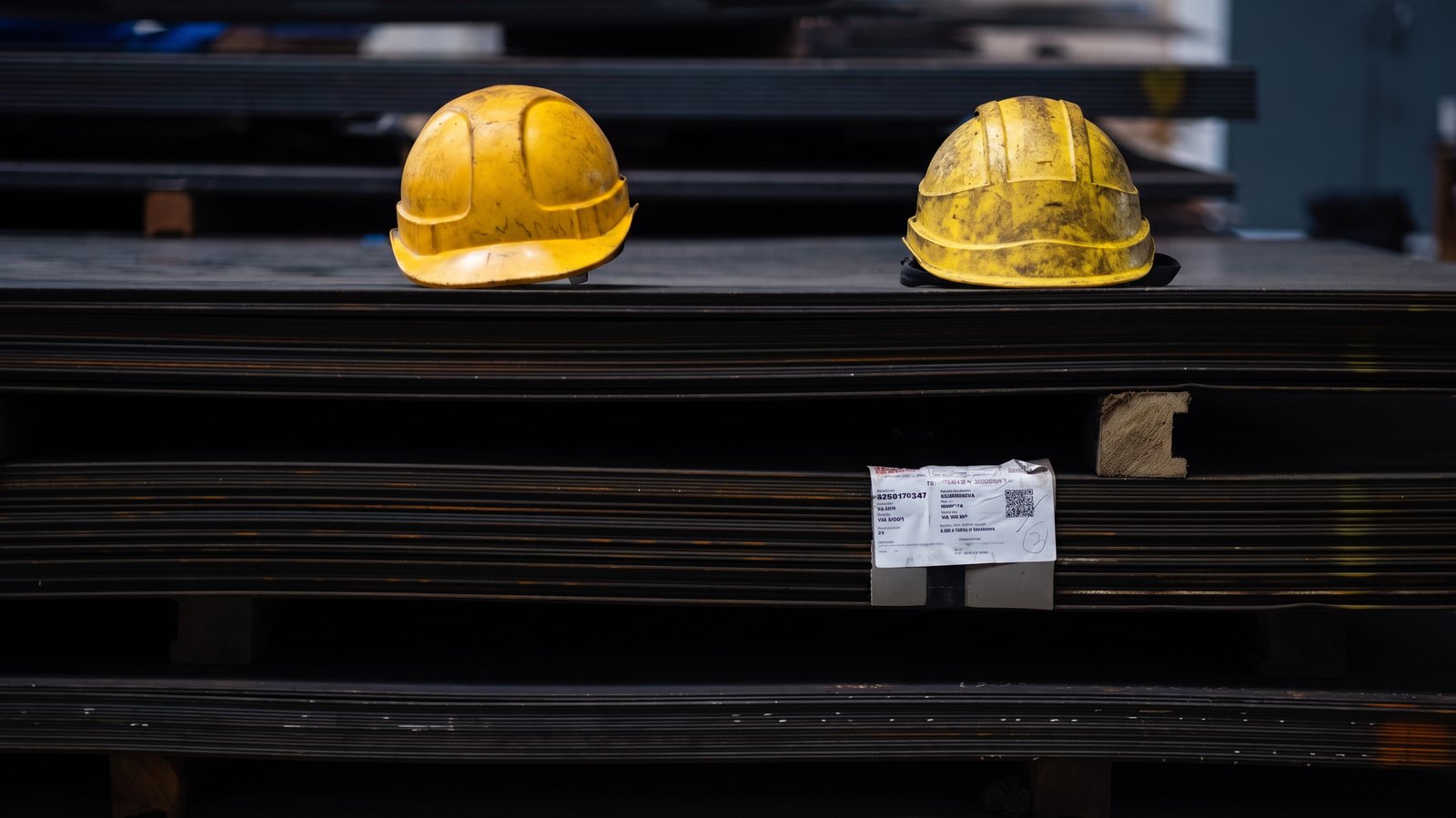 Steel sheet stock stacked in the plant, two hard hats resting on the top pack