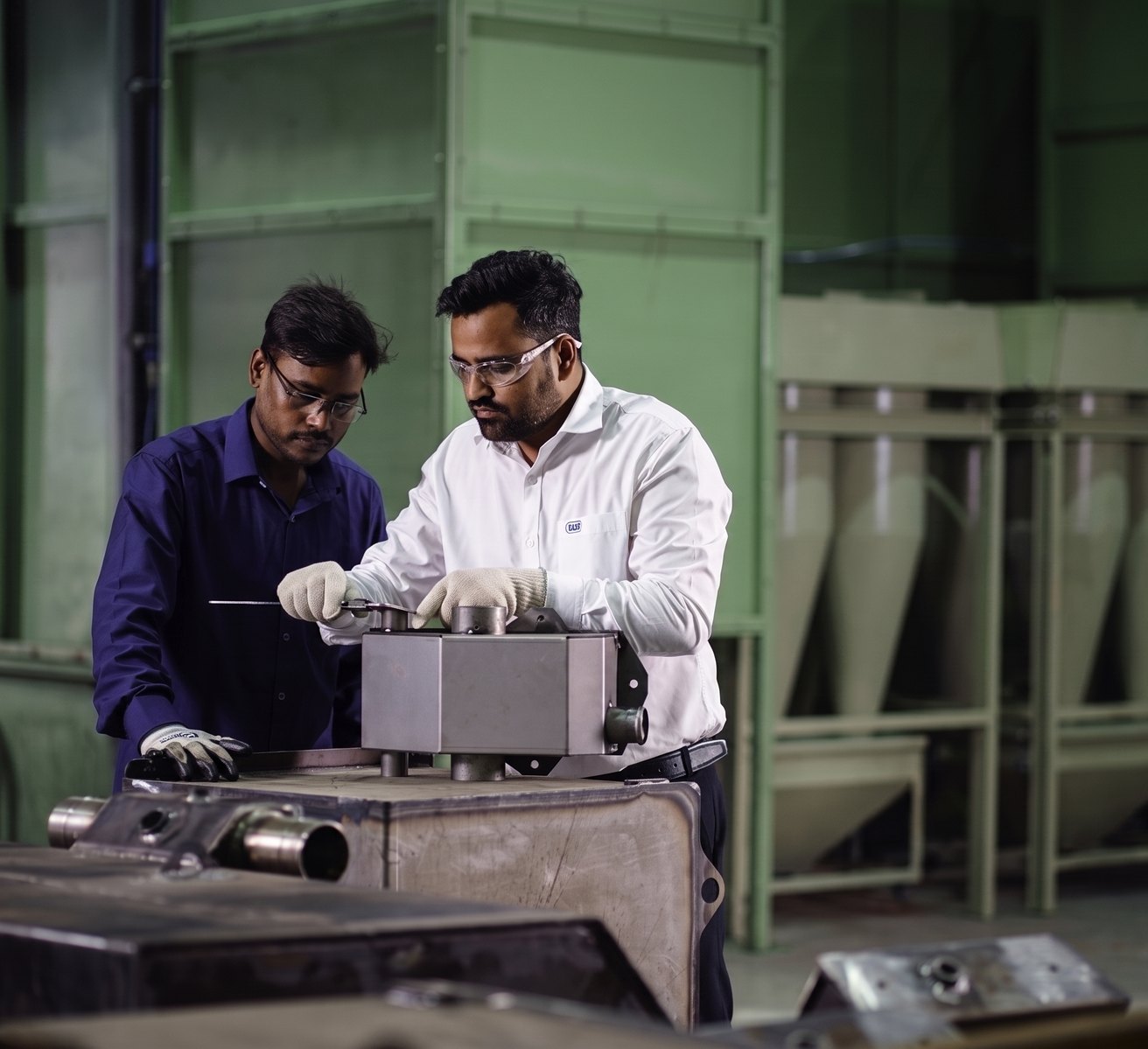 Two colleagues checking a machined component together at the bench