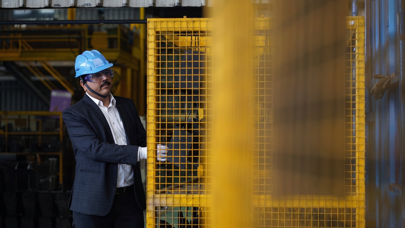 A Kelkar director beside a guarded machine on the plant floor